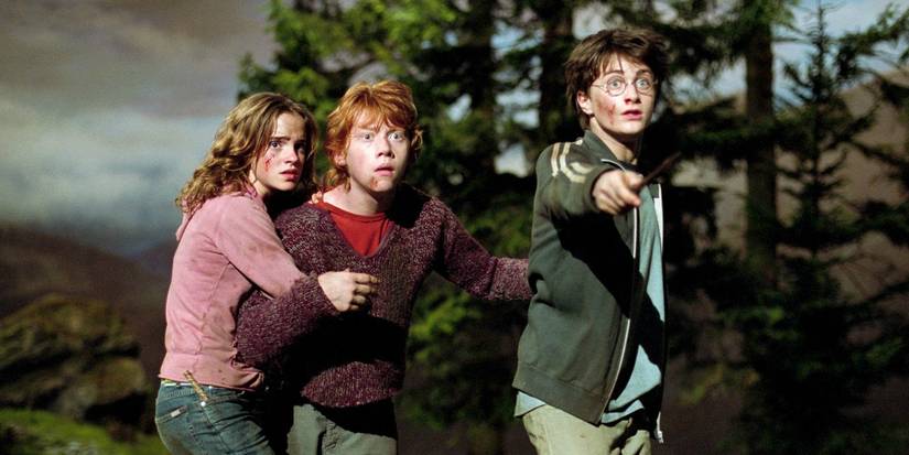 Daniel Radcliffe, Emma Watson, and Rupert Grint as Harry, Hermione, and Ron, looking scared as Lupin transforms into a werewolf in Harry Potter and the Prisoner of Azkaban