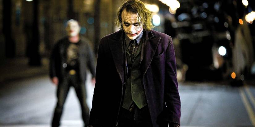 The Joker looking intently while standing on the street in The Dark Knight