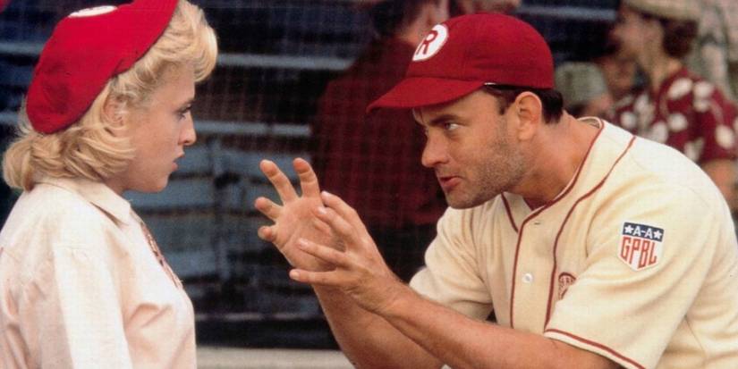 Jimmy Dugan (Tom Hanks) holding up his hands and talking to Evelyn Gardner (Bitty Schram) while they both wear their baseball uniforms in A League of Their Own