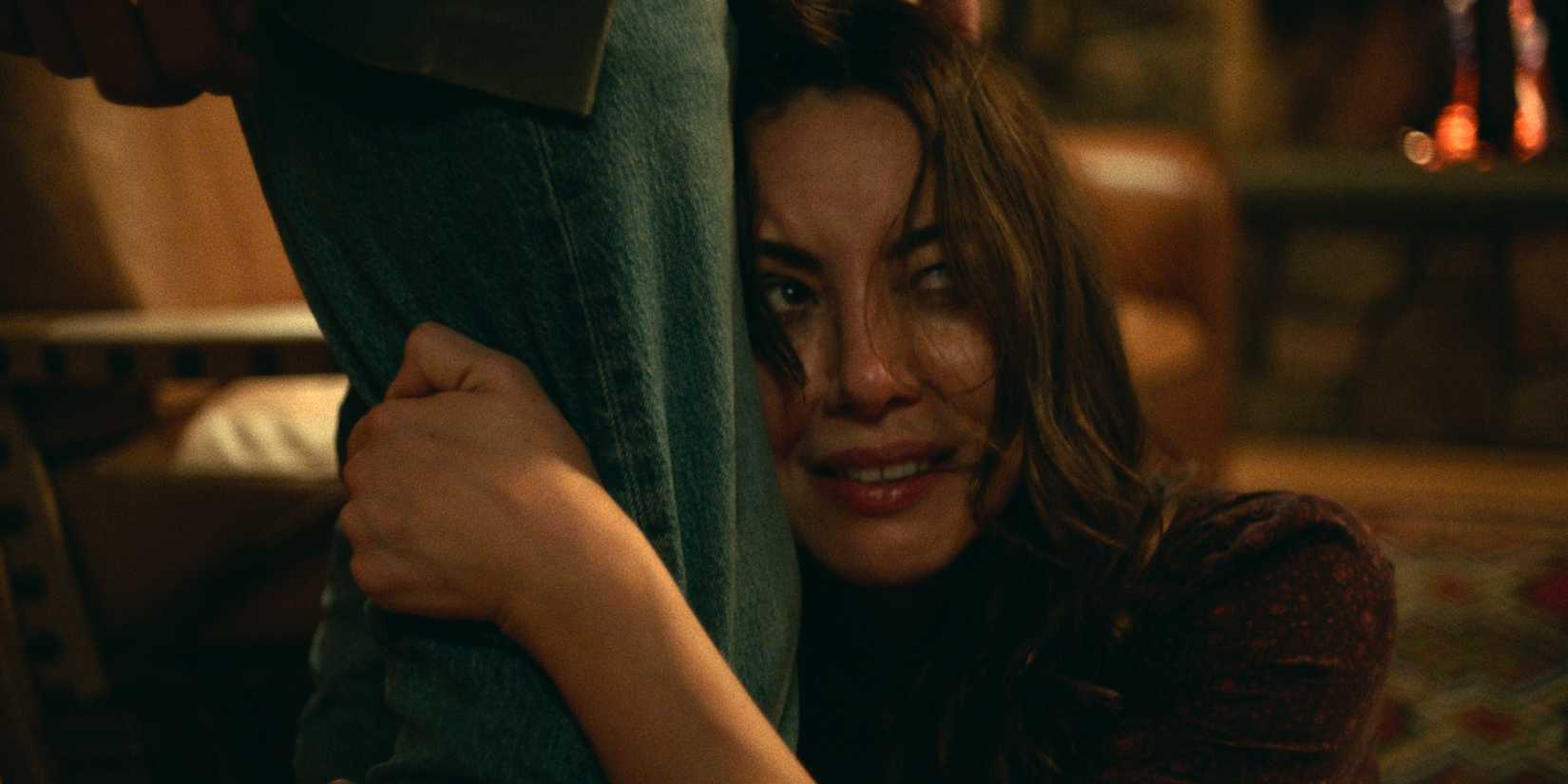 Allison crying while holding on to a man's leg in Black Bear.