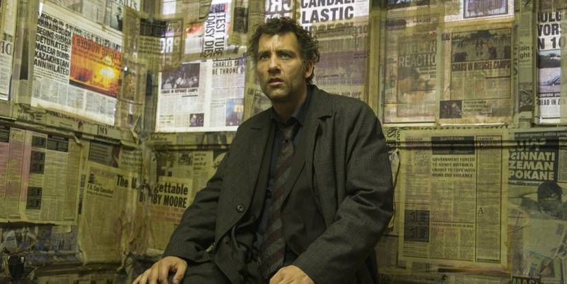 Clive Owen sitting down and looking confused in Children of Men