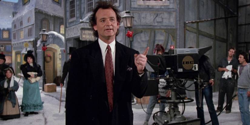 Bill Murray as Frank Cross holding a rose while standing on a commercial set in Scrooged.