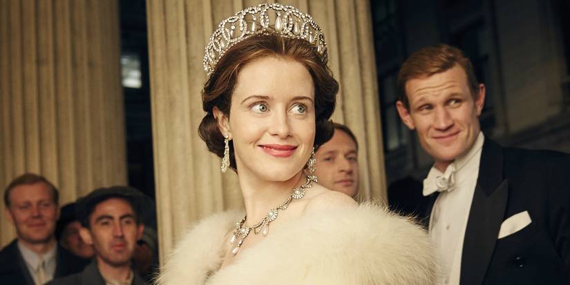 Claire Foy and Matt Smith dressed as their characters and smiling at a fancy party in The Crown.