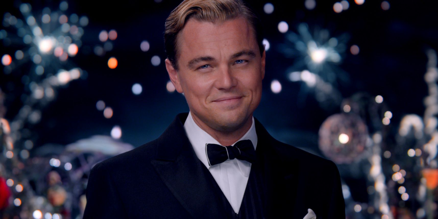 Jay Gatsby smiling with fireworks behind him in The Great Gatsby