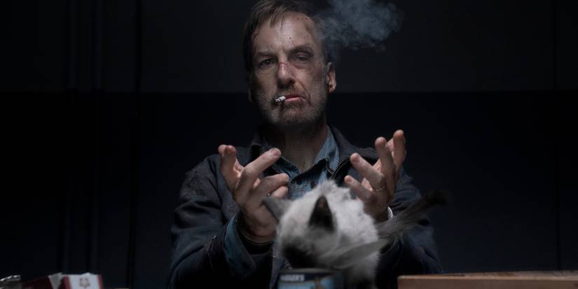 Bob Odenkirk sitting with both of his hands out and a cigarette in his mouth in Nobody