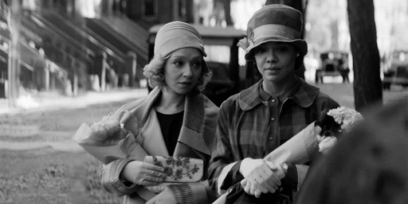 Ruth Negga and Tessa Thompson as Clare and Irene in a black and white setting walking down the street holding flowers.