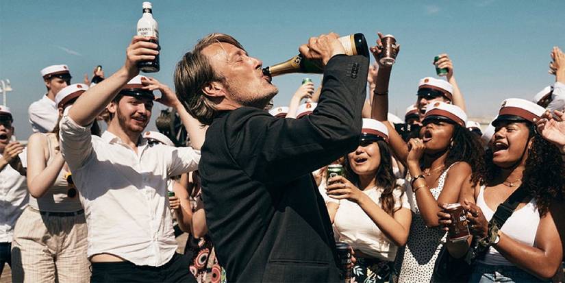Mads Mikkelsen as Martin drinking from a bottle of champaigne while a crowd cheers in Another Round