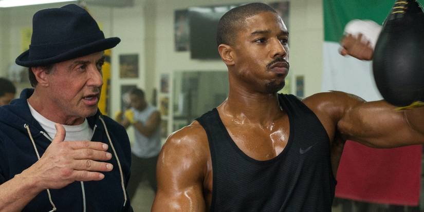 Rocky Balboa (Sylvester Stallone) coaching Adonis "Donnie" Creed (Michael B. Jordan) as he hits a speed bag in Creed