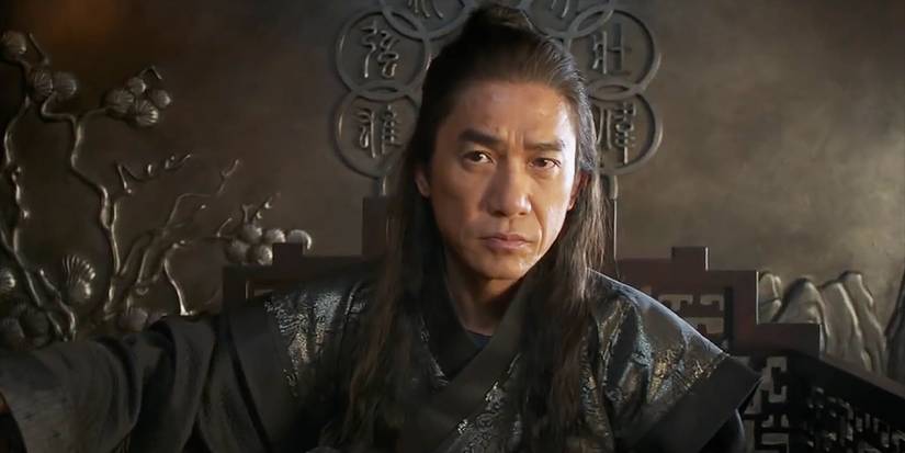 Xu Wenwu (Tony Leung Chiu-wai) sitting on his throne and looking at the camera in Shang-Chi and the Legend of the Ten Rings.