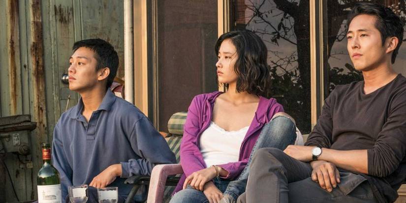 Jooh Ah-In as Lee, Jeon Jong-Seo as Shin and Stephen Yeun as Ben sitting on a porch in 'Burning'