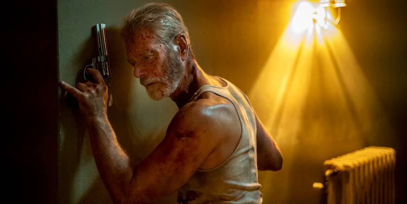 Stephen Lang holdin a gun while pressing his ear to a wall in Don't Breathe
