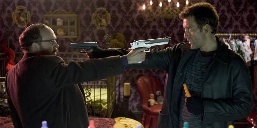 Paul Giamatti and Clive Owen pointing guns at each other in Shoot 'Em Up