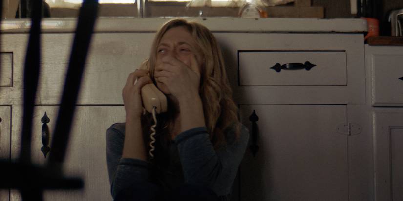 Louise, Marin Ireland, is on the phone, crying while sitting on the kitchen floor in the film The Dark and the Wicked.