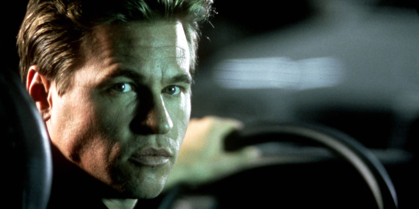 Simon Templar driving a car and looking to his back in The Saint