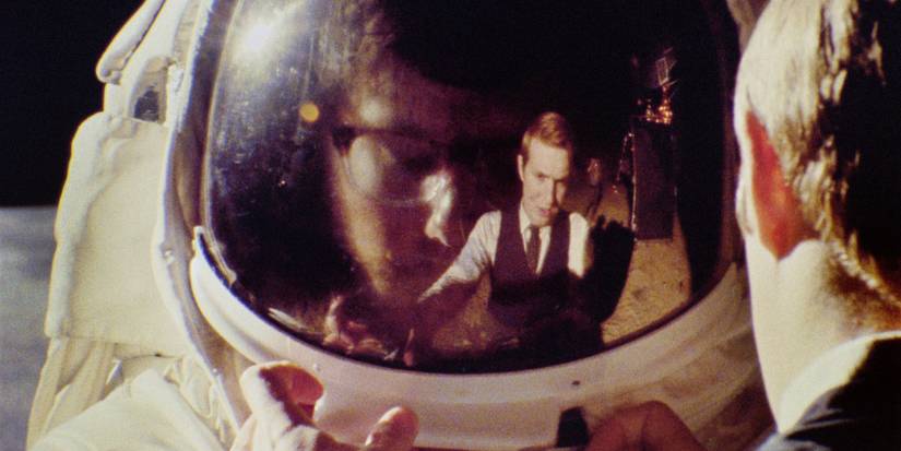 A gorup of suited men reflected on an astronaut's helmet in Operation Avalanche.