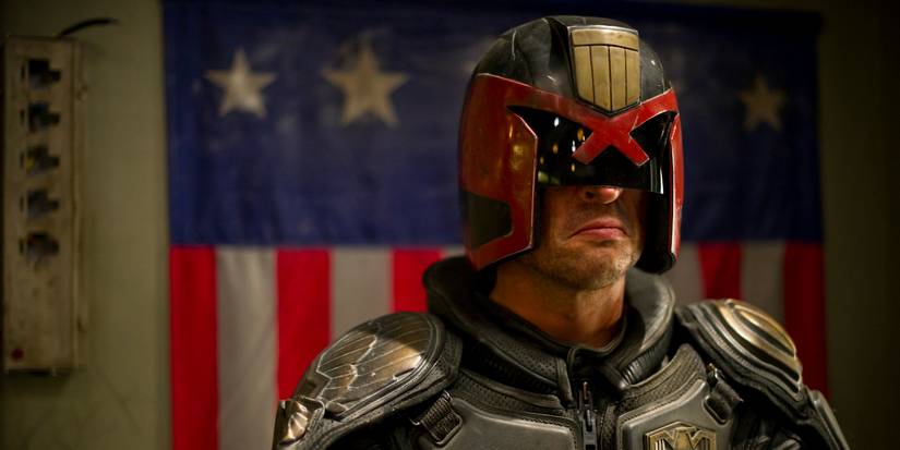 Judge Dredd looking ahead with an American flag behind him in Dredd.