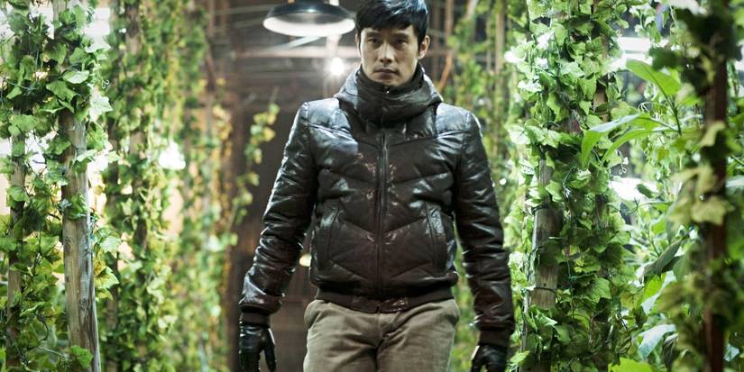 Lee Byng-hun walking down a leaf-covered hall in i-saw-the-devil