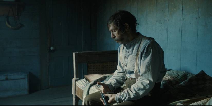 Tim Blake Nelson sitting on a bed, looking down, in 2021's Old Henry