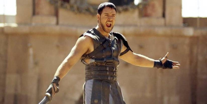 Maximus yelling and spreading his arms while holding a sword in Gladiator