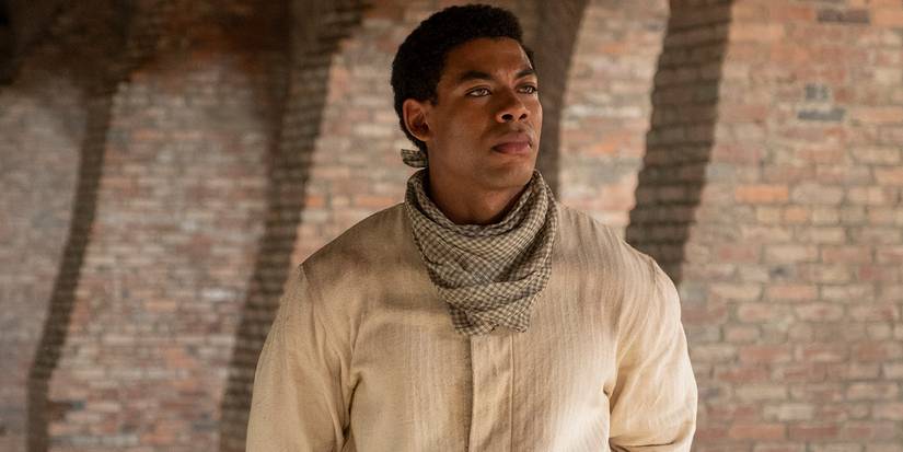 Caeser (Aaron Pierre) standing by a brick wall in The Underground Railroad.