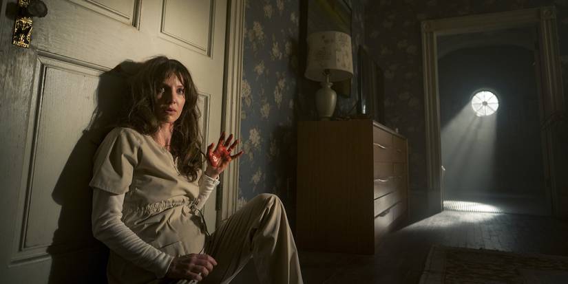 Annabelle Wallis sitting on the floor against a door in Malignant.