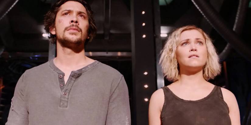 Clarke and Bellamy look concerned in the same direction in The 100.