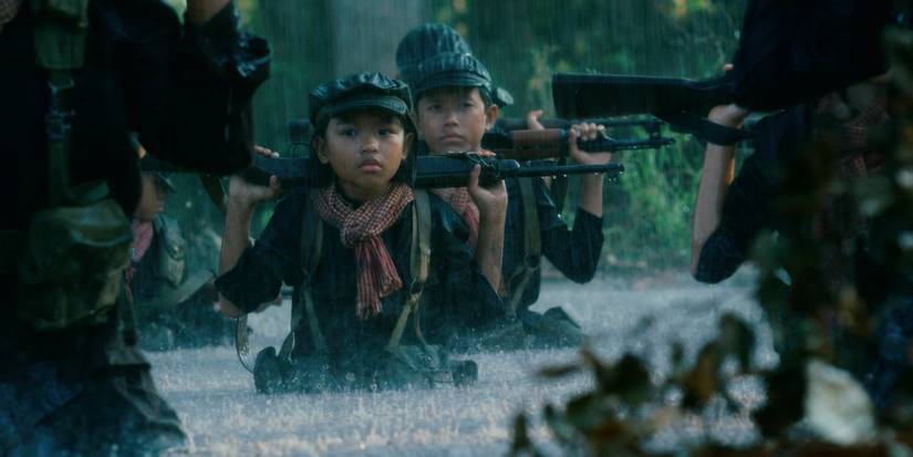 A group of child soldiers crossing a river while holding rifles in First They Killed My Father