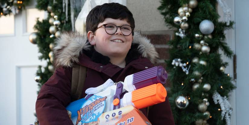 A young boy smiles and holds a toy gun in Home Sweet Home Alone