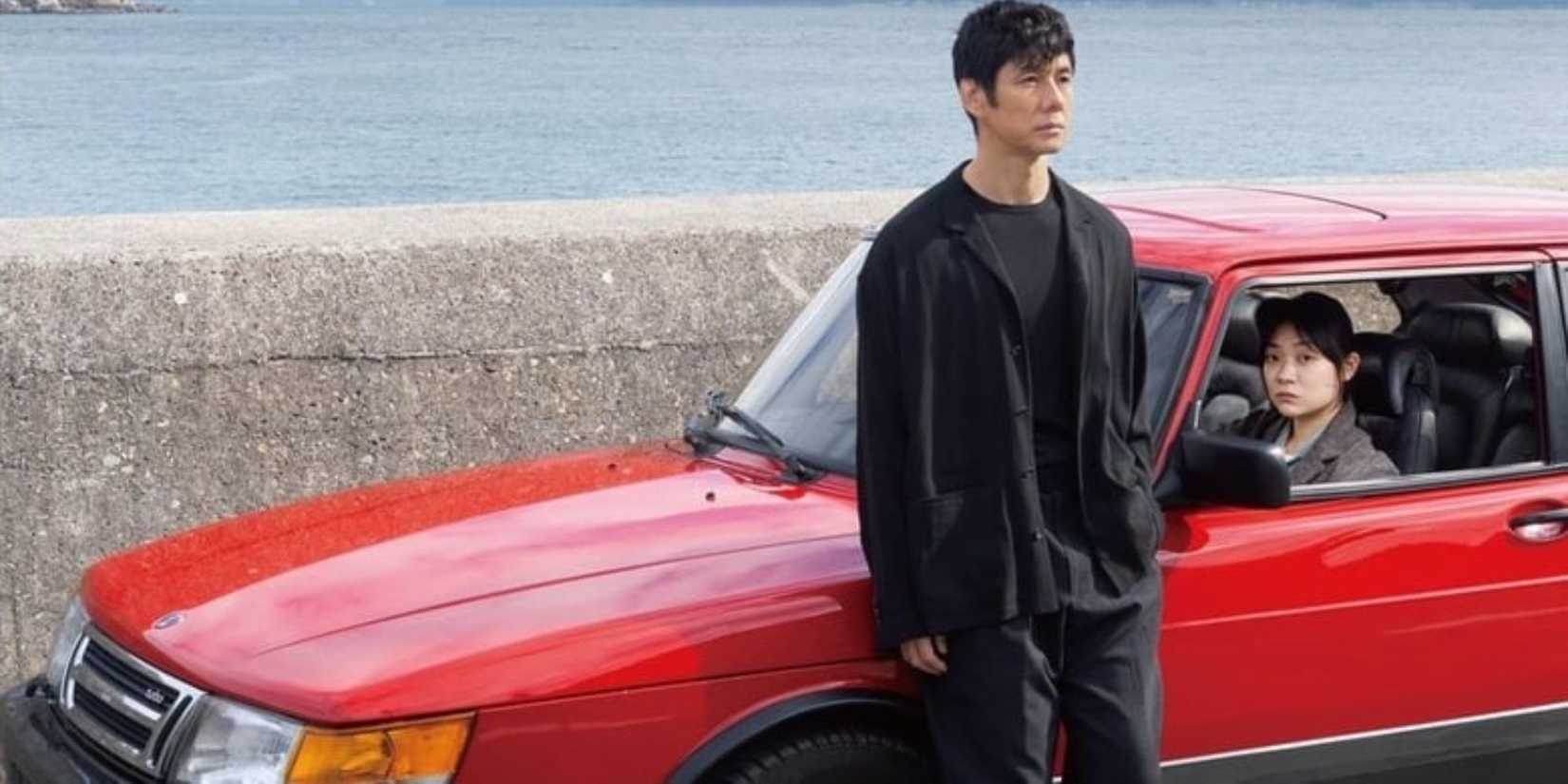 A man standing outside a car while a woman sits behind the sitrring wheel in Drive My Car