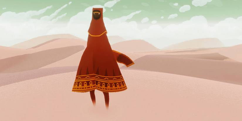 A gifure standing in a desert in the video game Journey