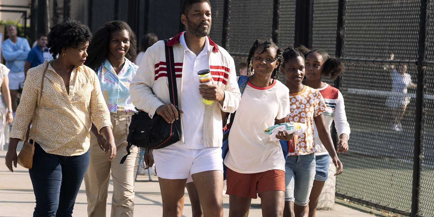 Will Smith as Richard Williams and Saniyya Sidney as Venus Williams walking past the tennis courts with the rest of the family in King Richard