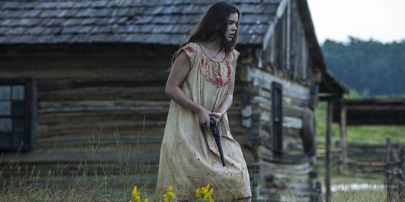 Louise (Hailee Steinfeld) holding a gun in a field in 'The Keeping Room'.