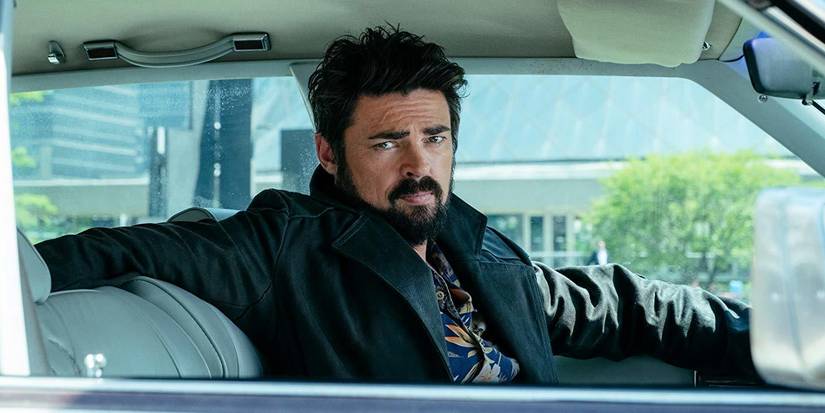 Karl Urban as Billy Butcher sits in a car, leaning back with his arm over the chair in The Boys.