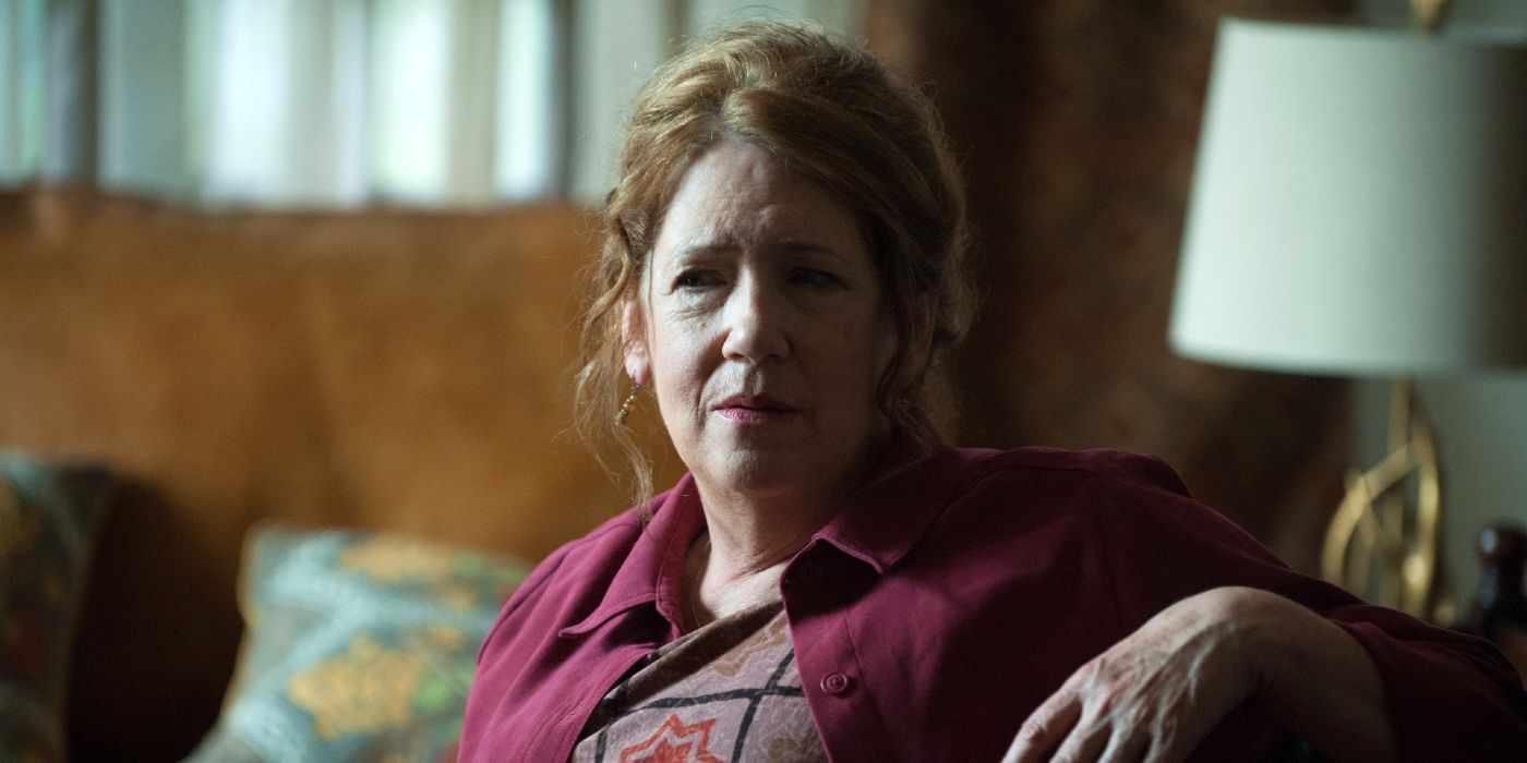 Ann Dowd as Joan sitting comfortably and looking at a person offscreen in Hereditary