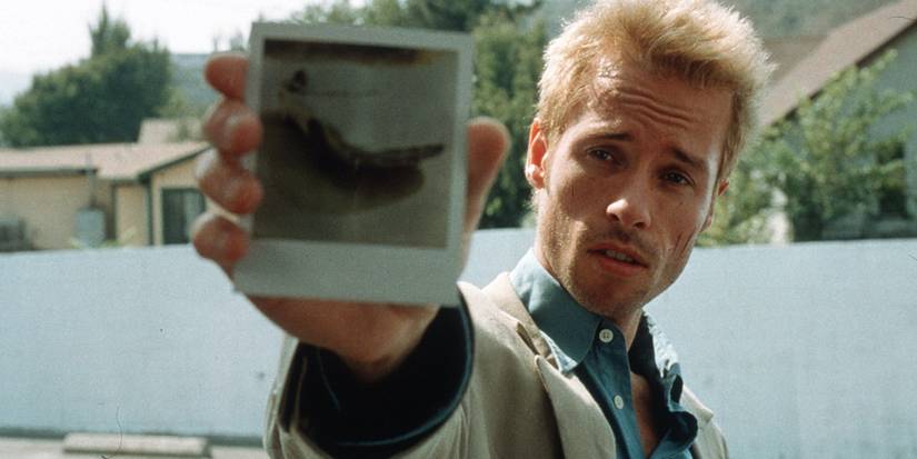 Guy Pearce as Leonard Shelby, holding out a polaroid in Memento.