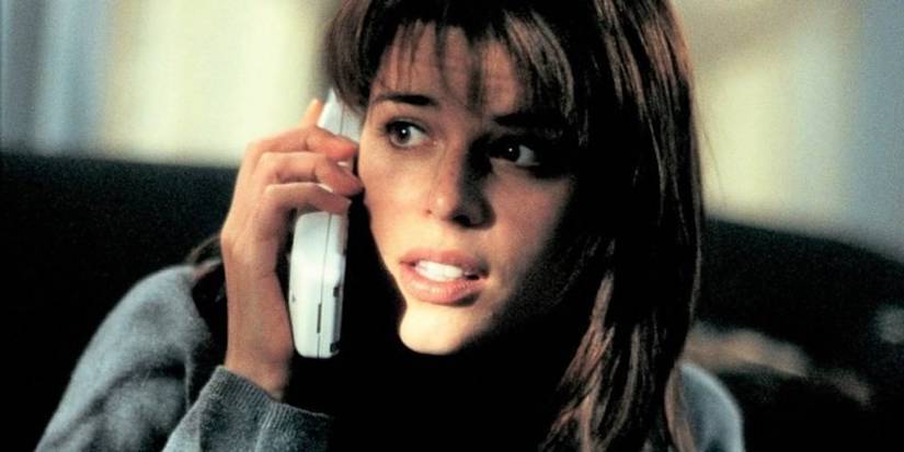 Neve Campbell on a phone looking concerned in 'Scream' as Sidney