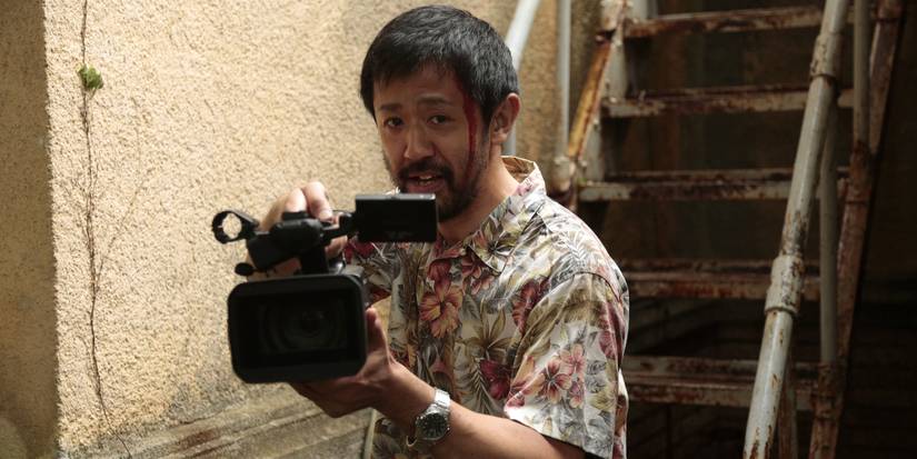 An injured man holding a film camera in One Cut of the Dead.