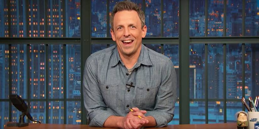 Seth Meyers talking to the camera at his desk. 