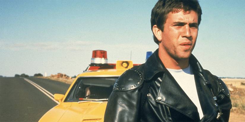 Mel Gibson as Max Rockatansky, standing on a road and looking concerned in Mad Max
