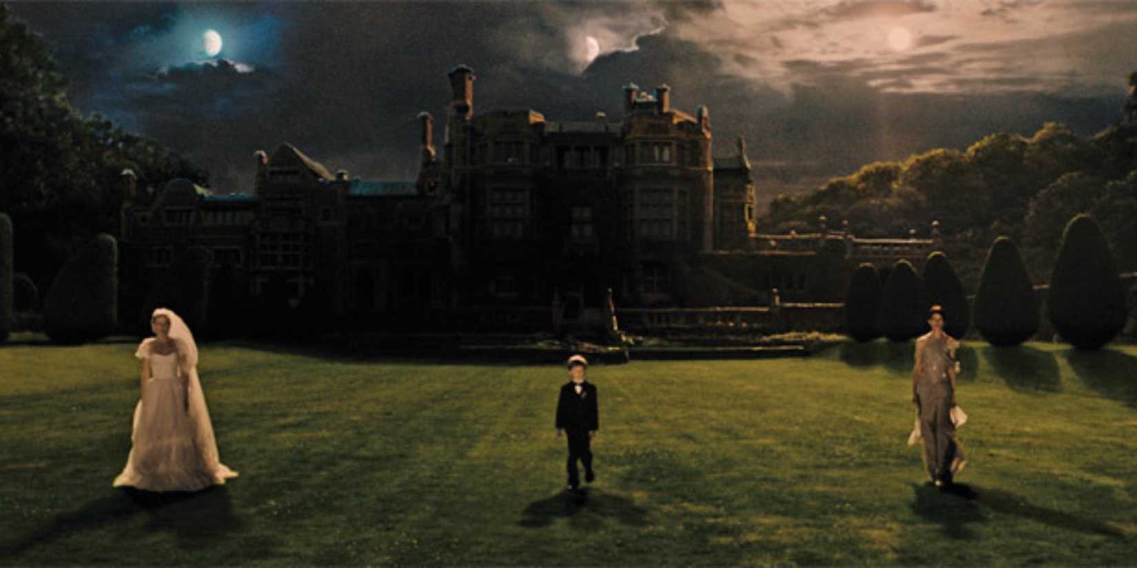 Two women and a child standing in a garden outside a castle in Melancholia