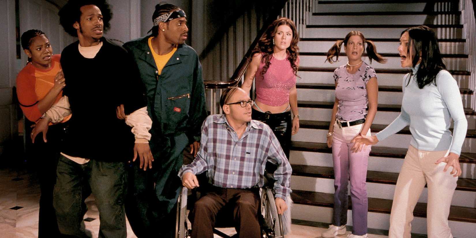 The main characters of Scary Movie 2 gathered at the bottom of a staircase looking scared.
