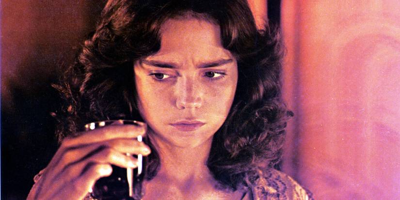 Suzy, played by actor Jessica Harper, looks suspiciously at a glass in her hand in Suspiria.