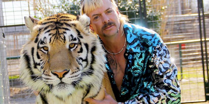 جو إكزوتيك يعانق نمرًا في مشهد من فيلم Tiger King