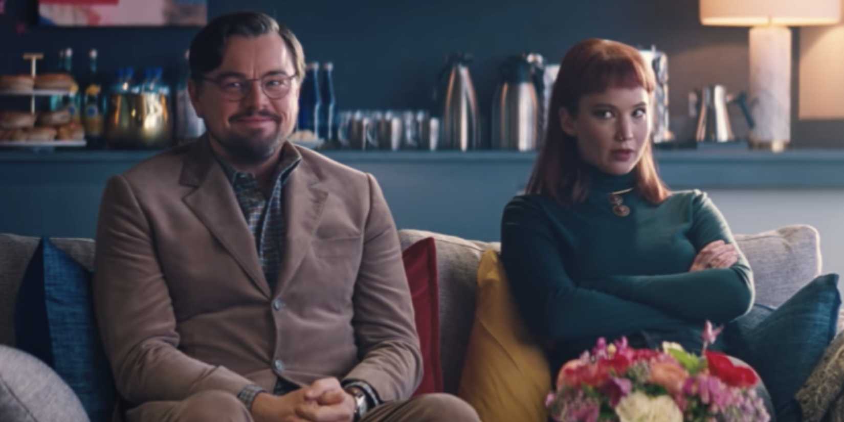Leonardo DiCaprio and Jennifer Lawrence sit on a sofa, waiting awkwardly, in Don't Look Up