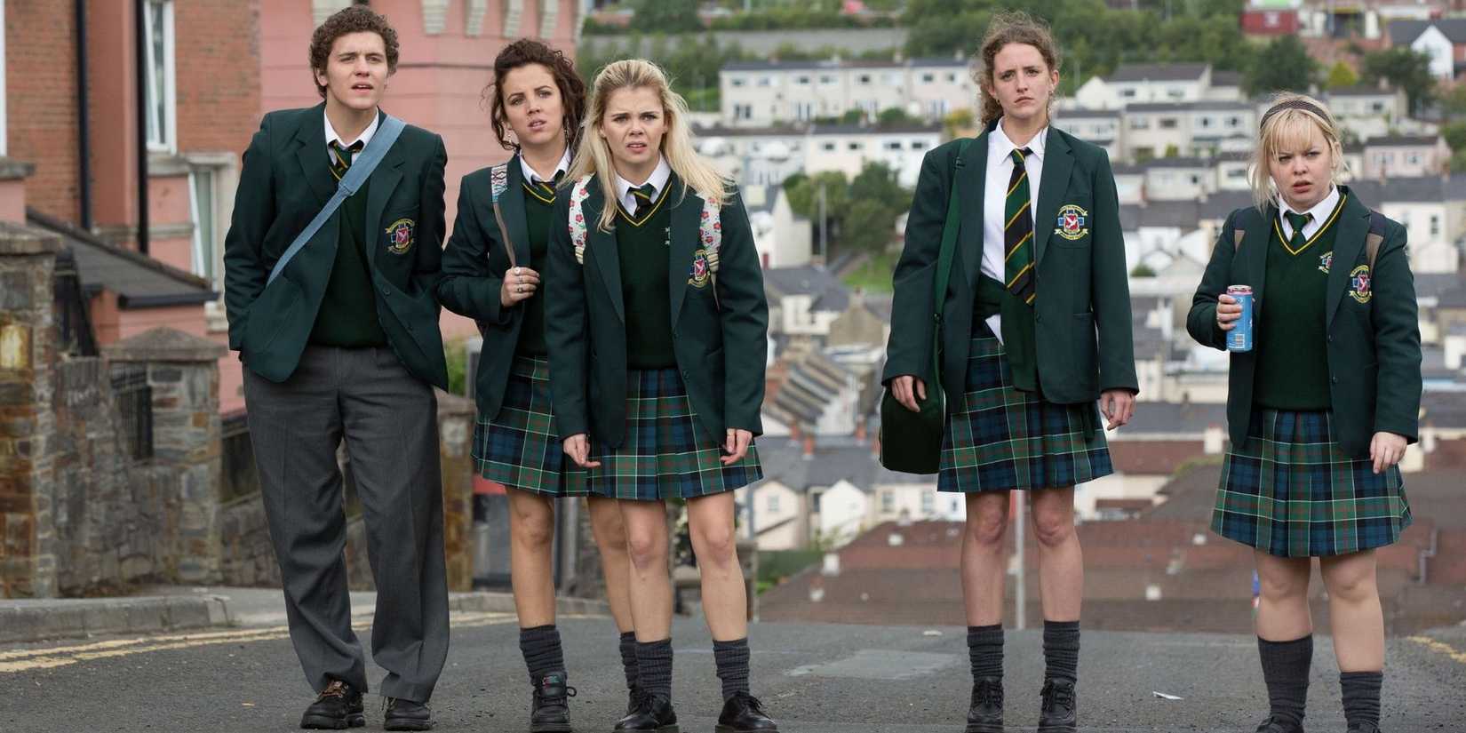 The cast of 'Derry Girls' stand in the middle of the street in their uniforms.
