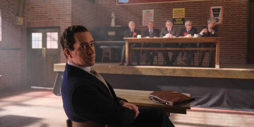 Matthew Macfayden in 'Stonehouse' staring back towards the camera while sitting at a small desk.