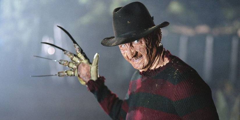 Freddy Krueger (Robert Englund) sorrindo e segurando a mão enluvada em um pesadelo na Elm Street