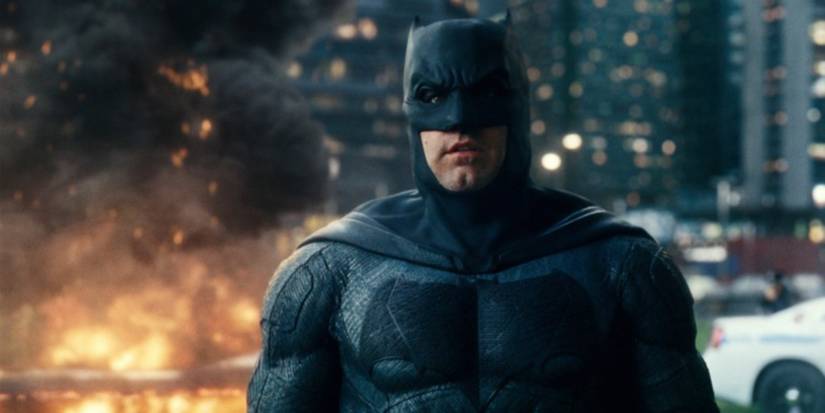 Batman looking ahead while an explosion rages behind him in Justice League