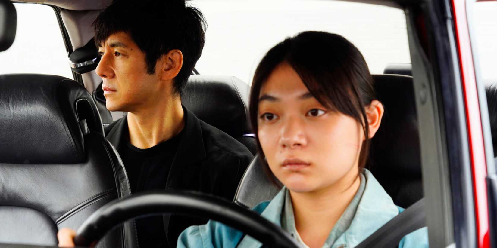 A woman drives a car with a man in the back seat in Drive My Car.