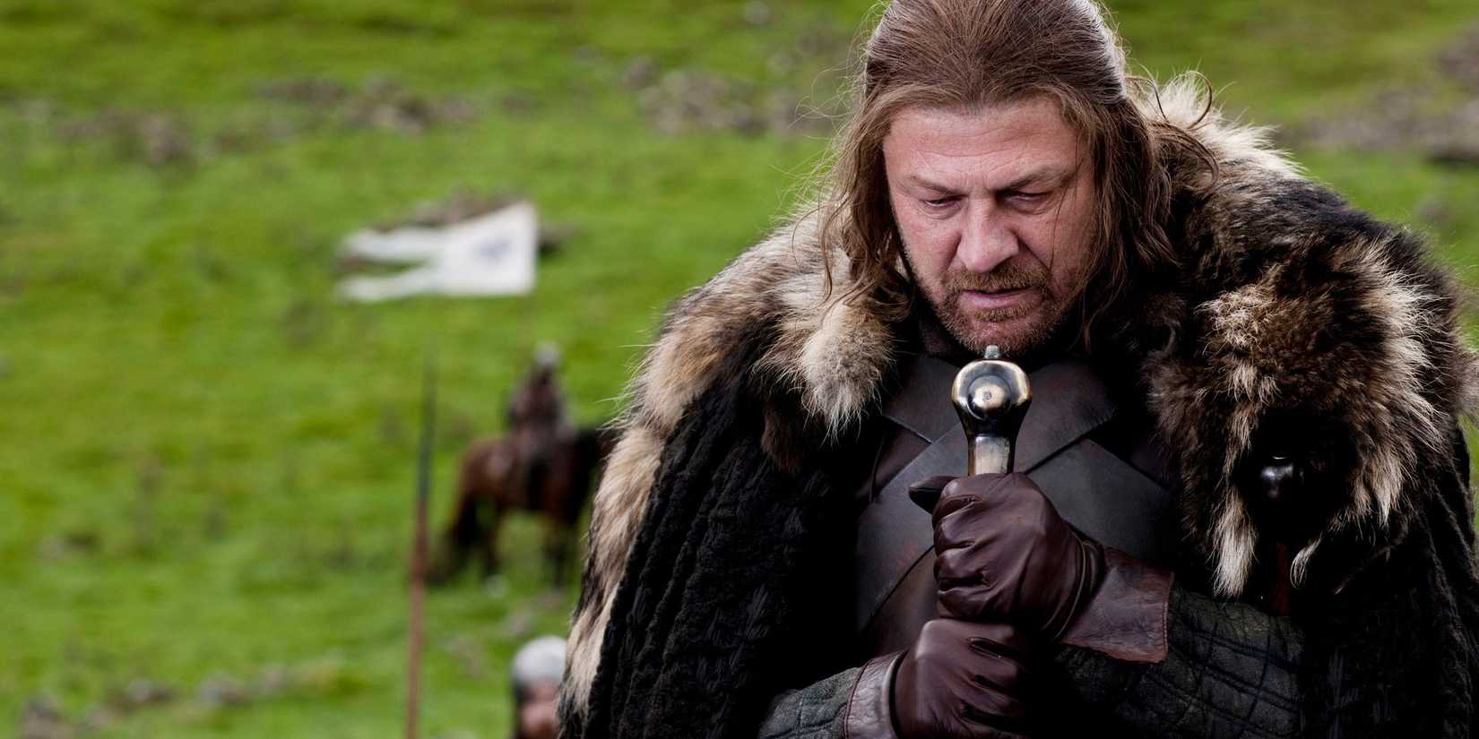 Ned Stark (Seasn Bean) holding a large sword while looking down in Game of Thrones